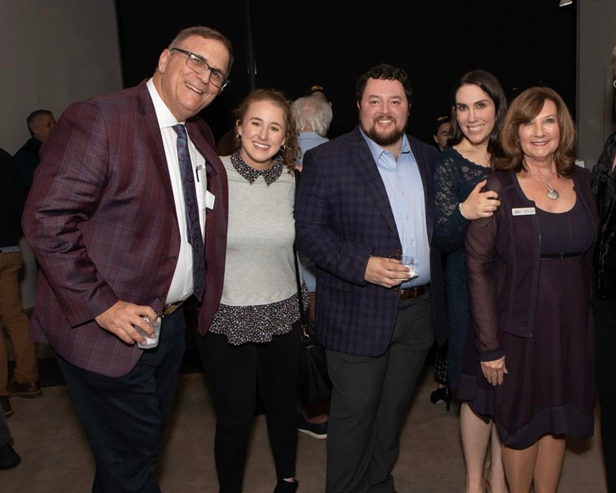 Group of five people posing together at an event.